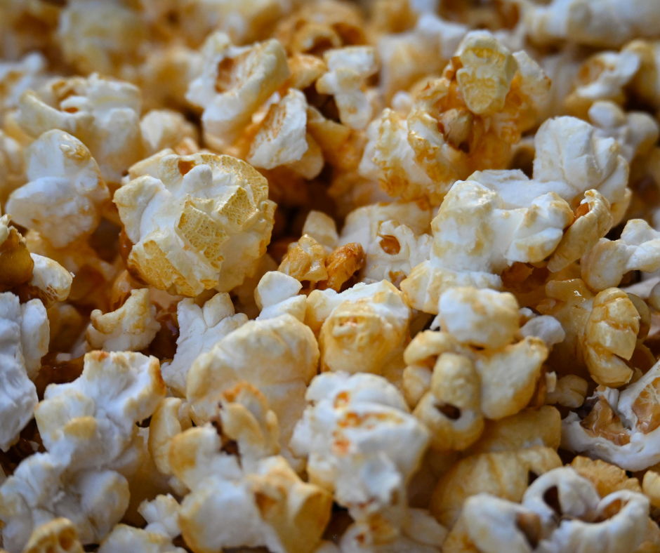 Close-up of freshly popped popcorn coated with a light caramel glaze, showing fluffy white kernels and golden-brown pieces in sharp detail.