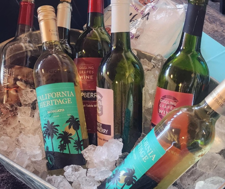 Assorted bottles of wine chilling in a metal tub filled with ice, featuring red, white, and sweet wines ready for serving.
