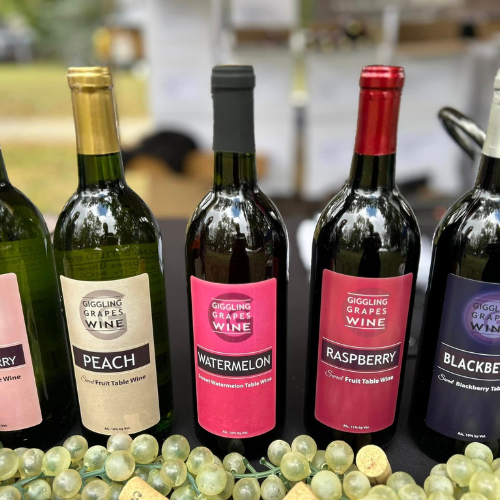 Giggling Grapes fruit wines including peach, watermelon, raspberry, and blackberry displayed with fresh grapes
