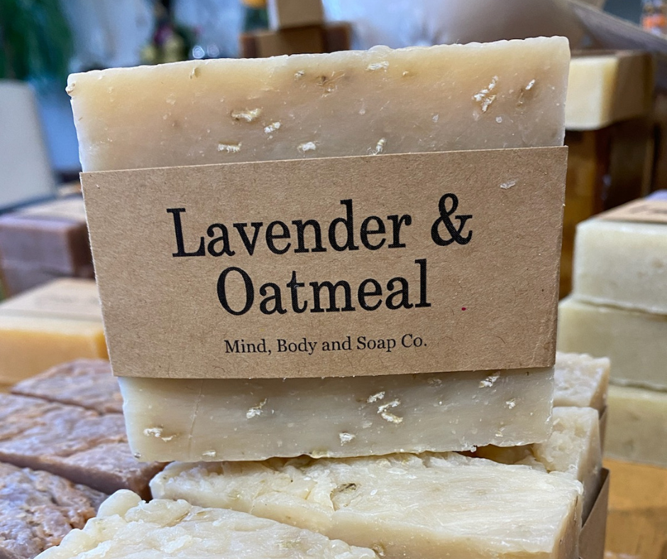 Handcrafted lavender and oatmeal soap bars stacked on display, wrapped in simple kraft paper labels.