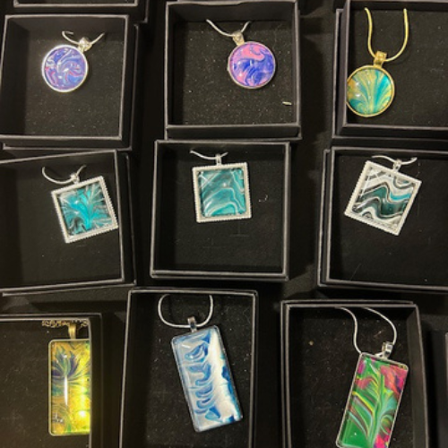 Handcrafted pendant necklaces with colorful abstract designs displayed in black gift boxes