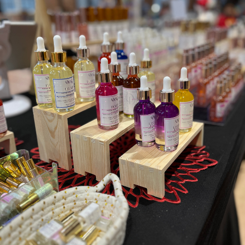 Colorful skincare serums with droppers displayed on wooden stands at a vendor booth