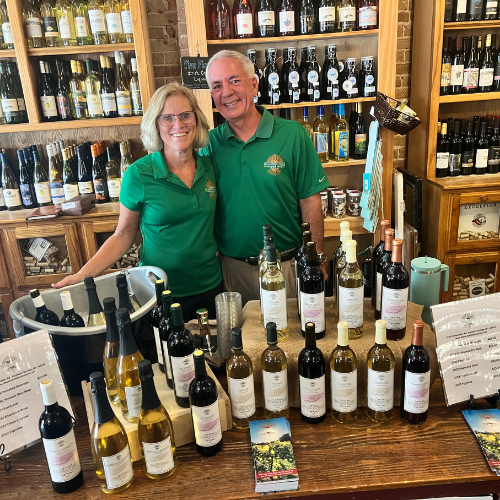 Owners at Shamrock Hills Vineyard and Winery standing behind a wine tasting display with bottles inside a shop