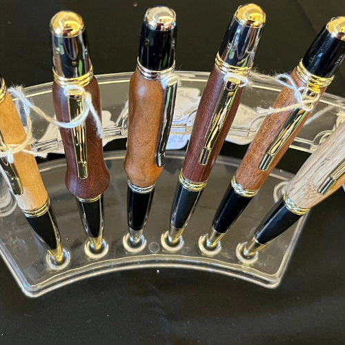 Handcrafted wooden pens with polished finishes displayed on a stand by Sosnowski Custom Pens