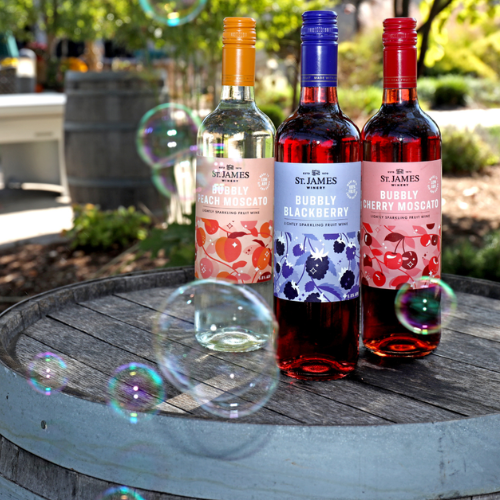 St. James Winery bubbly wines including peach moscato, blackberry, and cherry displayed on a barrel outdoors