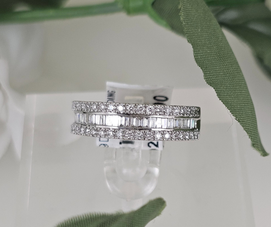 Close-up of a diamond band ring featuring sparkling pavé and baguette-cut stones displayed on a jewelry stand.