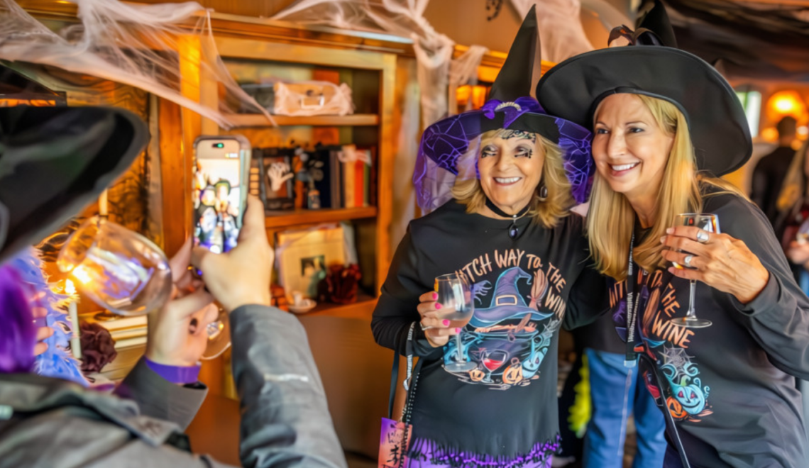 Two women dressed as witches pose with wine glasses during the Witch Way to the Wine event in Downtown Excelsior Springs.