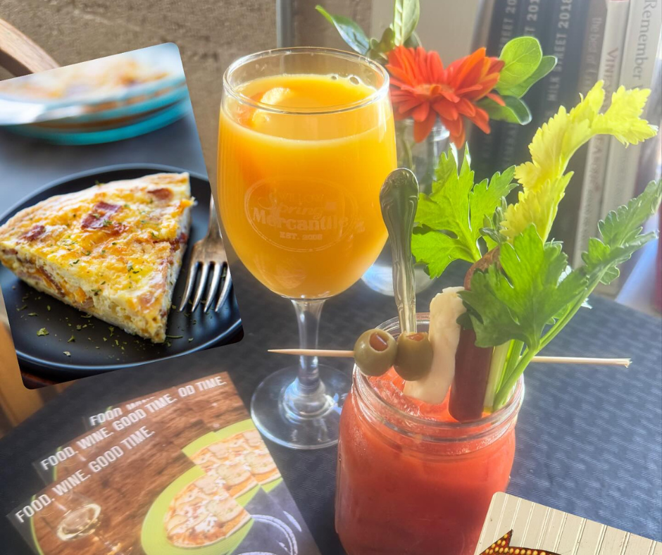 Brunch spread featuring a Bloody Mary garnished with celery and olives, a mimosa, and a slice of quiche served in a cozy café setting.