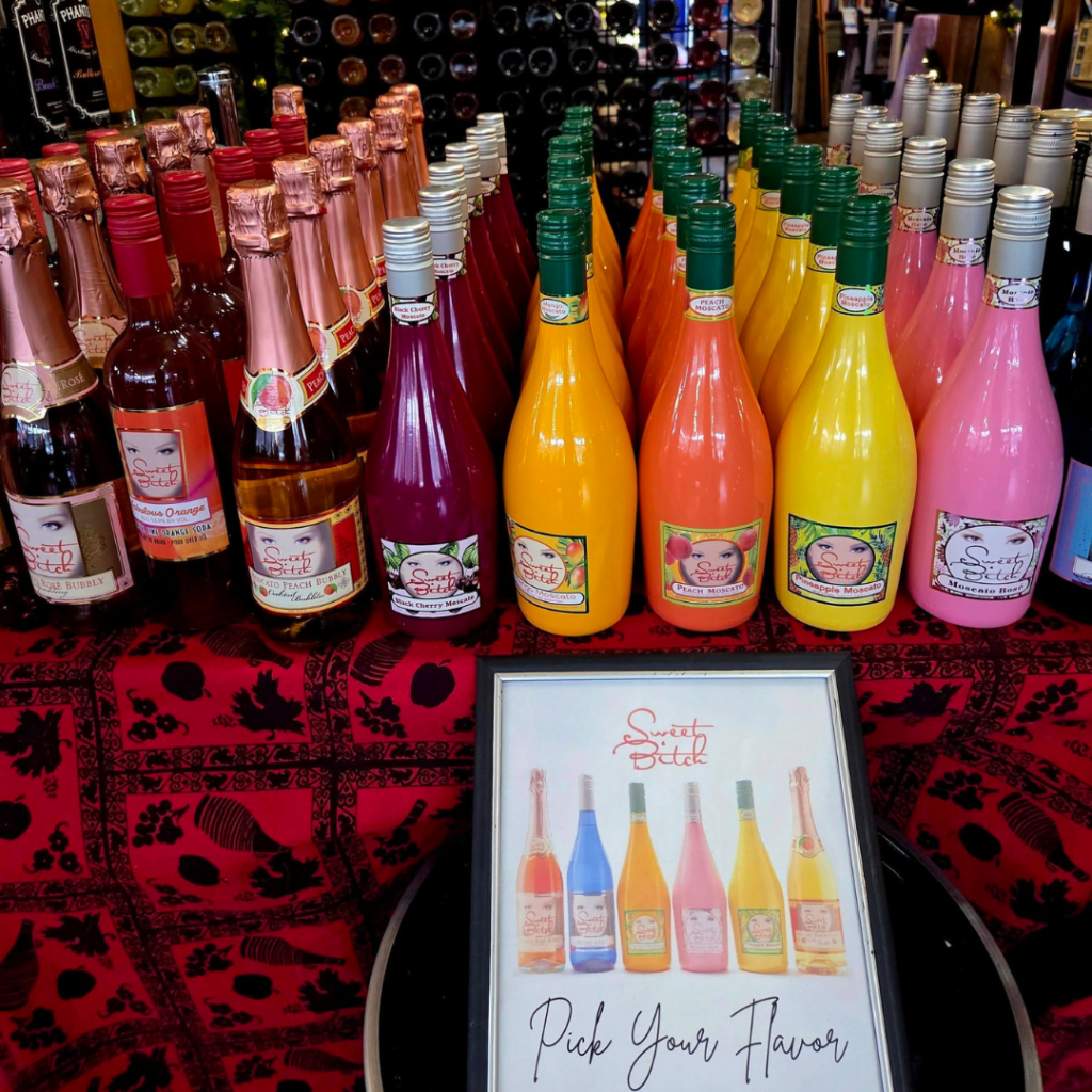 Display of colorful Sweet Bitch wine bottles at Wine & Shine Tasting Room in downtown Excelsior Springs.