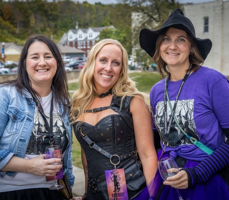 Three friends pose with wine glasses during Witch Way to the Wine in Downtown Excelsior Springs.