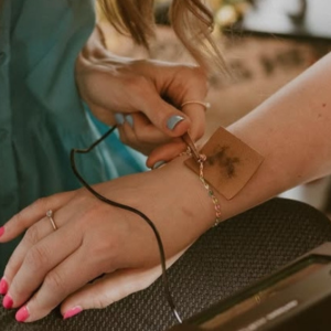 Close-up of a permanent jewelry bracelet being welded onto a customer’s wrist during a permanent jewelry experience at a boutique.