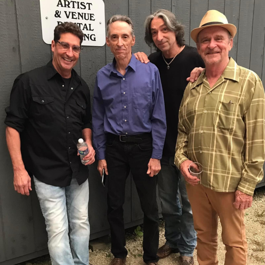 Members of The Nace Brothers pose together backstage before a live performance, standing in front of an artist and venue parking sign.
