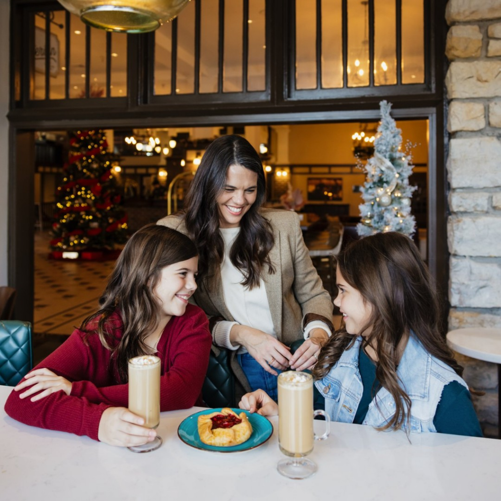 A mother and two children share coffee drinks and pastries inside The Elms Hotel & Spa, showcasing family-friendly hospitality in Excelsior Springs.