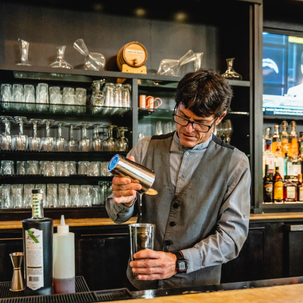 A bartender prepares a handcrafted cocktail at The Elms Hotel & Spa, offering guests a premium food and beverage experience in Downtown Excelsior Springs.