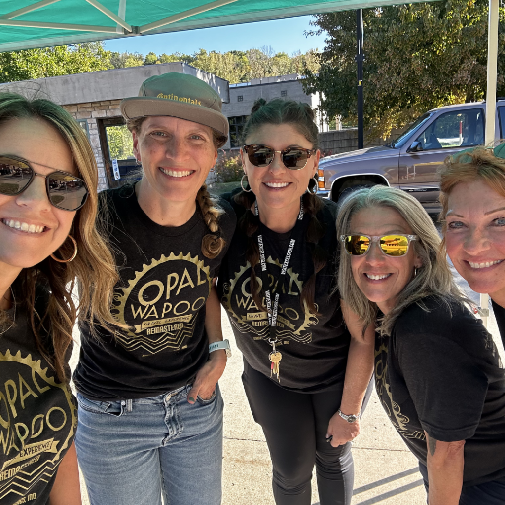 Volunteers wearing Opal Wapoo Gravel Experience shirts assist with event operations, helping welcome cyclists and support the community cycling event.