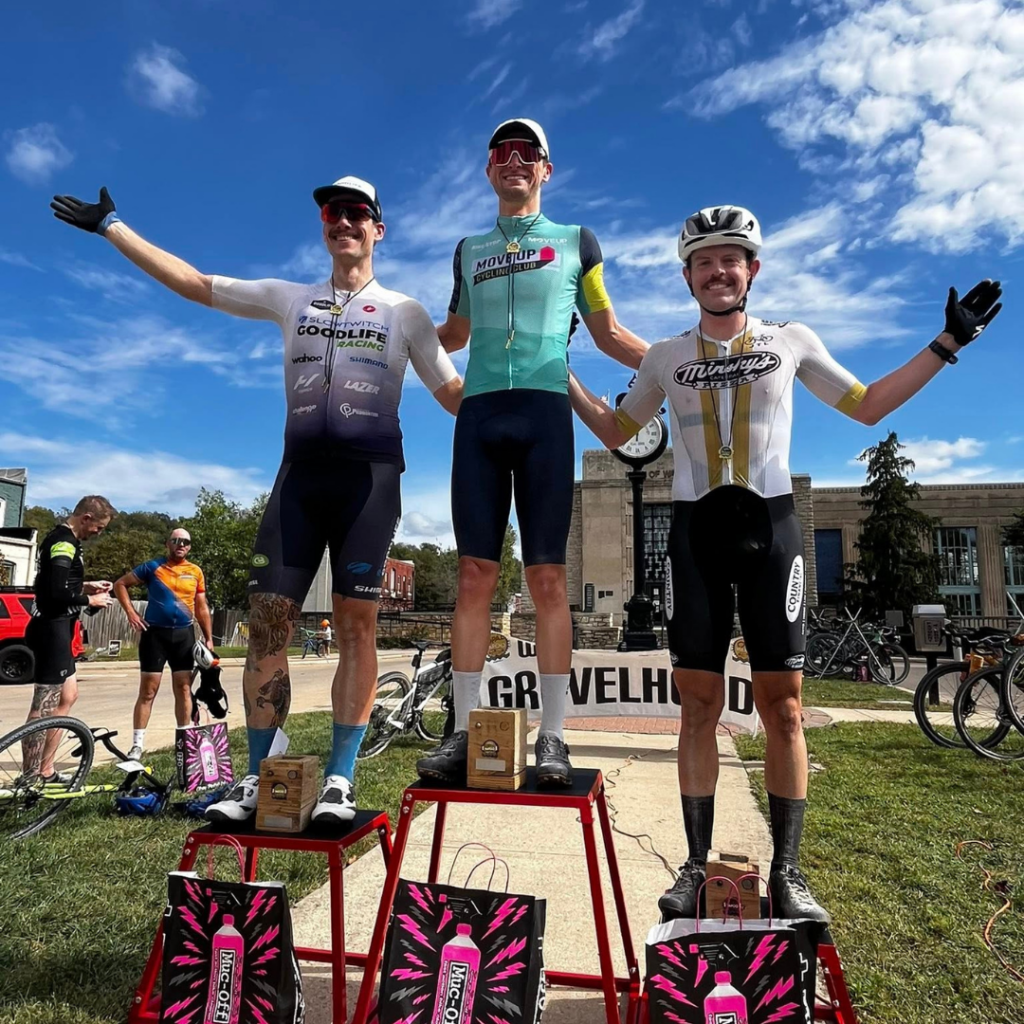 Top finishers celebrate on the awards podium following the Opal Wapoo Gravel Experience in Excelsior Springs, Missouri.