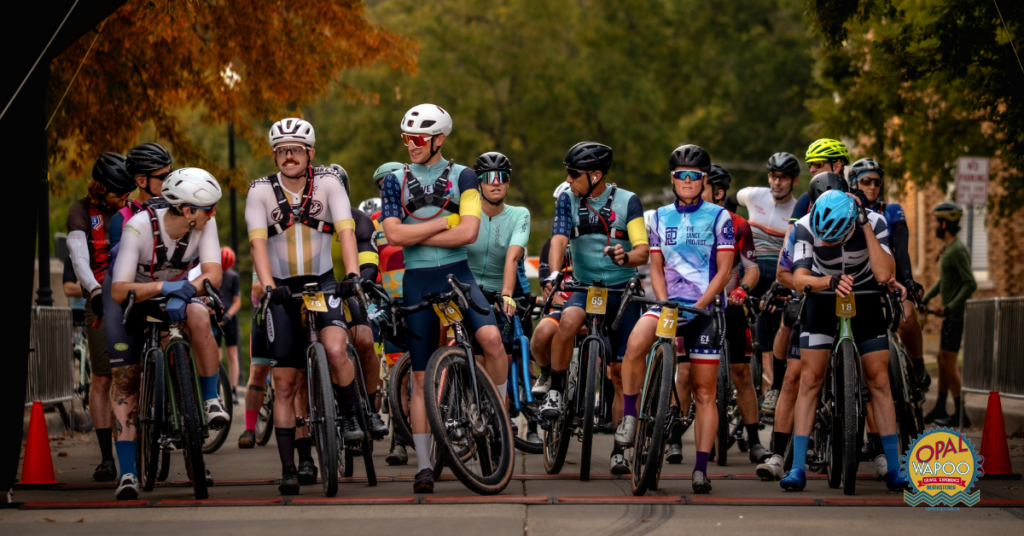 Cyclists gather at the starting line of the Opal Wapoo Gravel Experience in Downtown Excelsior Springs, preparing to ride scenic gravel roads through rural Missouri.