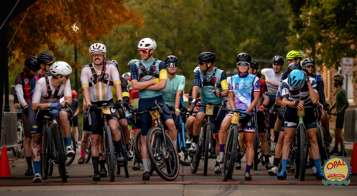 Cyclists gather at the starting line of the Opal Wapoo Gravel Experience in Downtown Excelsior Springs, preparing to ride scenic gravel roads through rural Missouri.