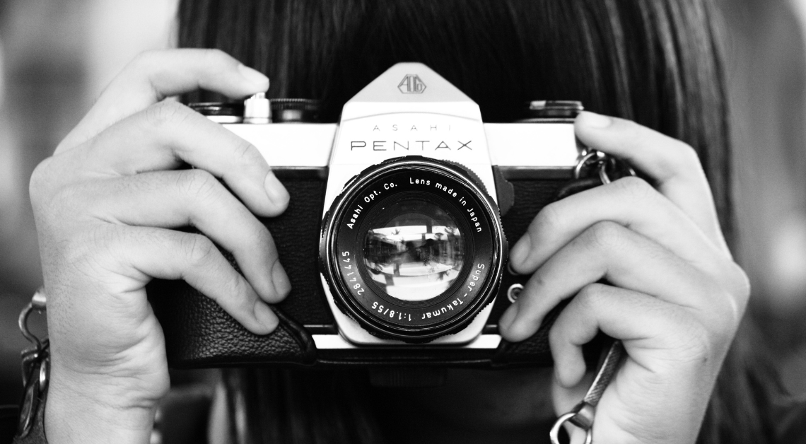 A close up photograph of a person's hands holding a camera.